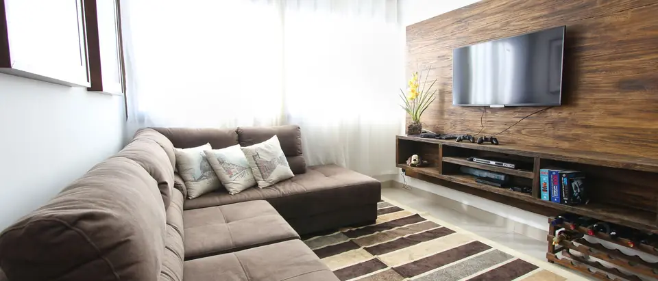 A furnished living room with a sofa, a rug and sheer curtains