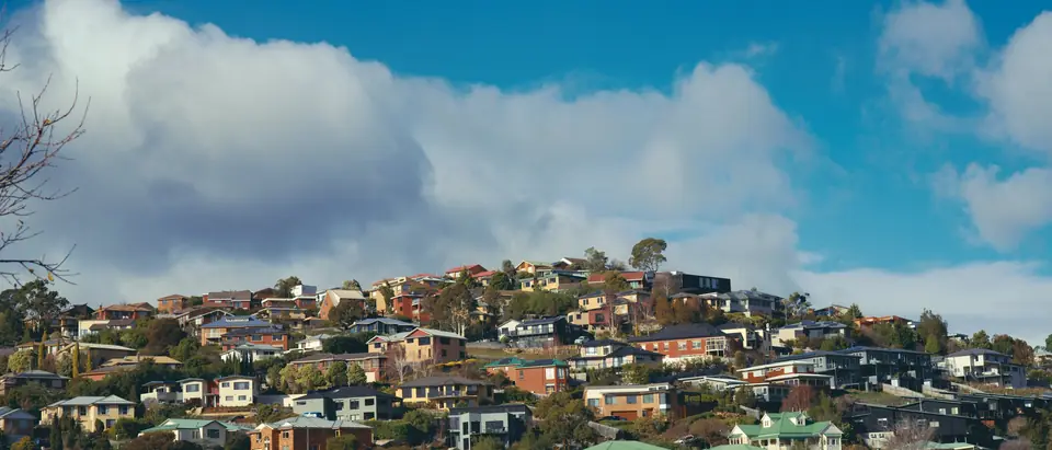 Houses spread across a hillside under a blue sky with white clouds